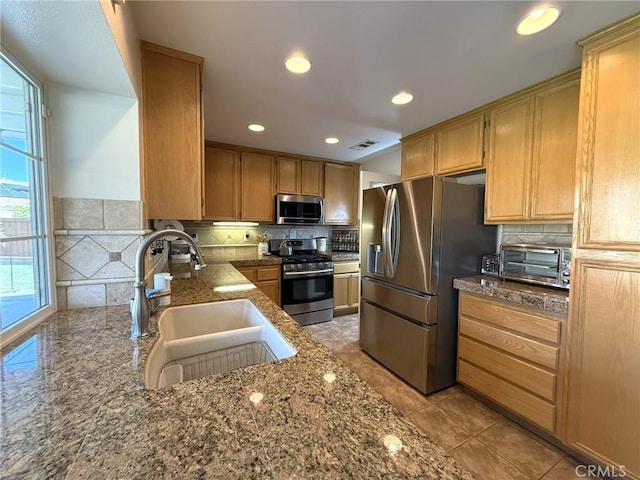 kitchen with tasteful backsplash, a sink, visible vents, stainless steel appliances, and a toaster
