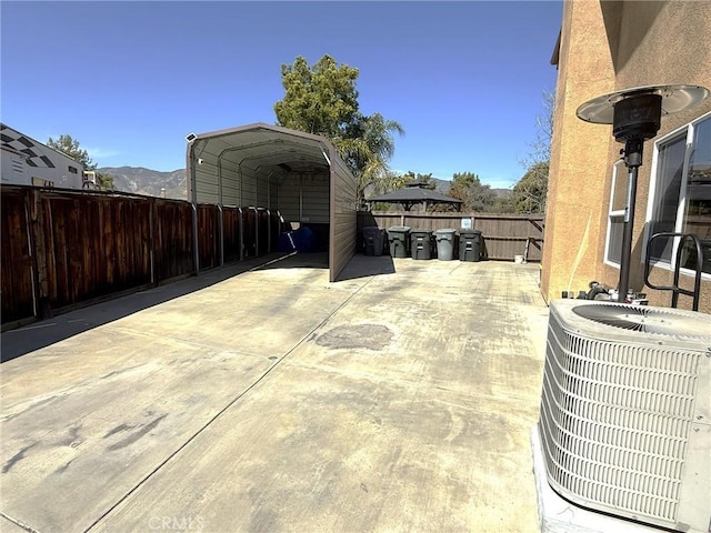 view of patio with a detached carport, a fenced backyard, and central AC unit