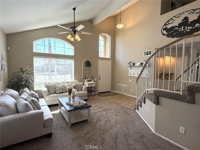 living area with a wealth of natural light, visible vents, a ceiling fan, and stairway