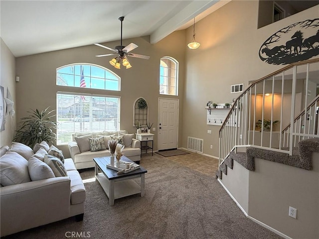 carpeted living room with stairs, visible vents, ceiling fan, and high vaulted ceiling