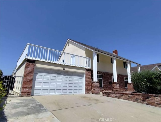 view of front of property with a balcony, a chimney, driveway, and brick siding