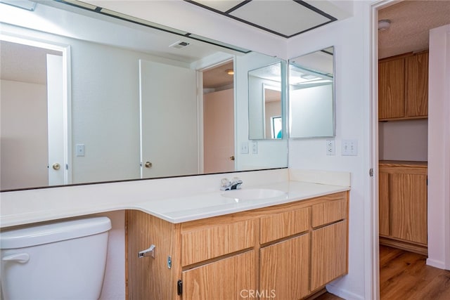 bathroom with wood finished floors, toilet, and vanity