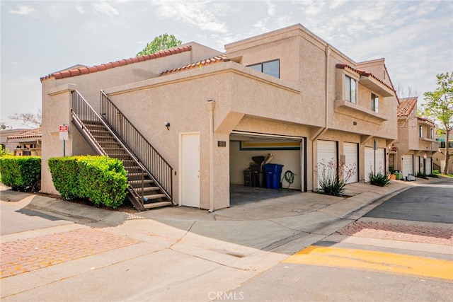 view of building exterior featuring driveway, stairway, and an attached garage