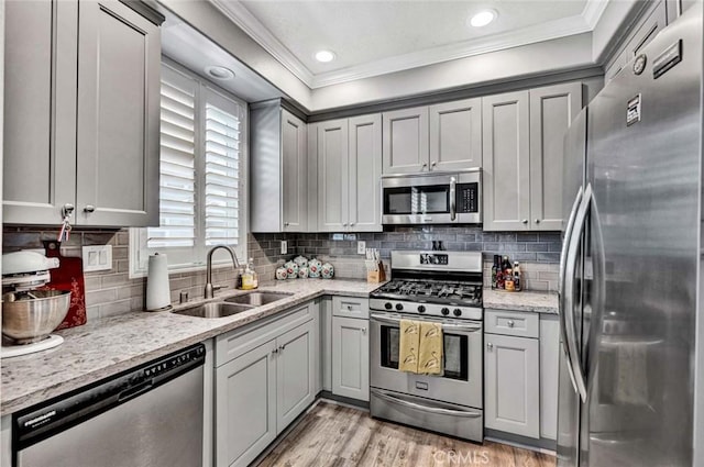 98 Hinterland Way, Ladera Ranch, CA 92694 - kitchen featuring a sink, ornamental molding, light wood-type flooring, appliances with stainless steel finishes, and light stone countertops