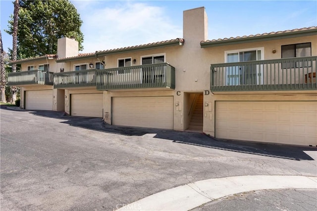 87 Tennessee St Unit C, Redlands, CA 92373 - view of front of home featuring a chimney, stucco siding, a tile roof, and a balcony
