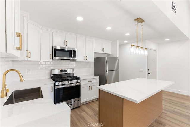 87 Tennessee St Unit C, Redlands, CA 92373 - kitchen with stainless steel appliances, a sink, light wood finished floors, white cabinetry, and backsplash