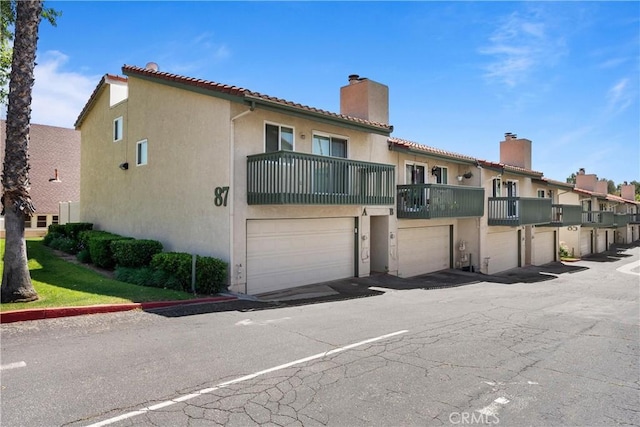 87 Tennessee St Unit C, Redlands, CA 92373 - rear view of house with a chimney, a balcony, an attached garage, stucco siding, and a tiled roof