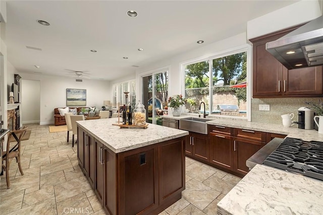 44 Edenbrook, Irvine, CA 92620 - kitchen featuring stone tile floors, wall chimney range hood, a center island, a sink, and backsplash