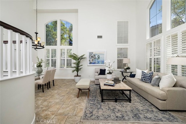 44 Edenbrook, Irvine, CA 92620 - living area featuring stone finish flooring, a notable chandelier, visible vents, and a high ceiling
