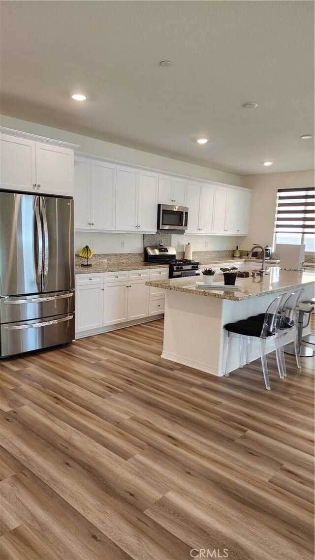 30874 Windy Ridge Way, Menifee, CA 92584 - kitchen featuring appliances with stainless steel finishes, white cabinetry, a breakfast bar area, light stone counters, and recessed lighting