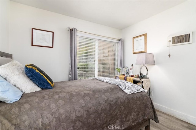 bedroom with visible vents, baseboards, and wood finished floors