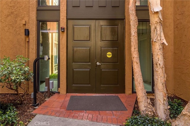 property entrance featuring stucco siding and french doors