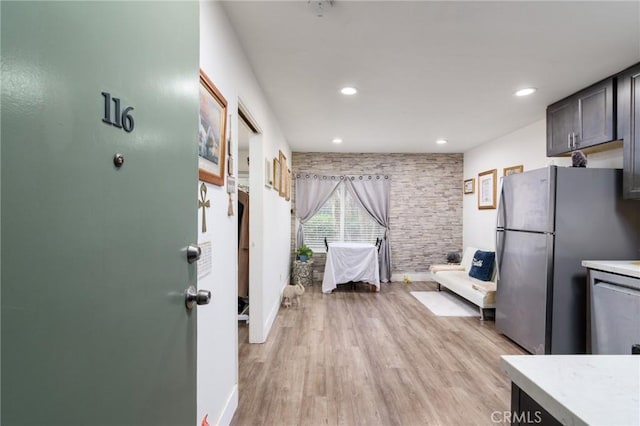 kitchen featuring baseboards, light countertops, light wood finished floors, recessed lighting, and stainless steel appliances