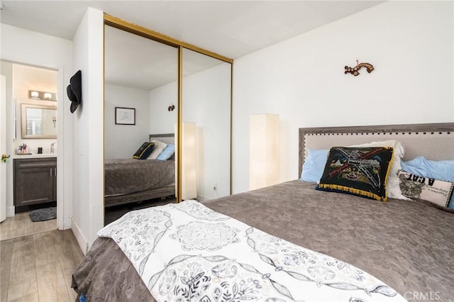 bedroom featuring light wood-type flooring, a closet, and ensuite bathroom