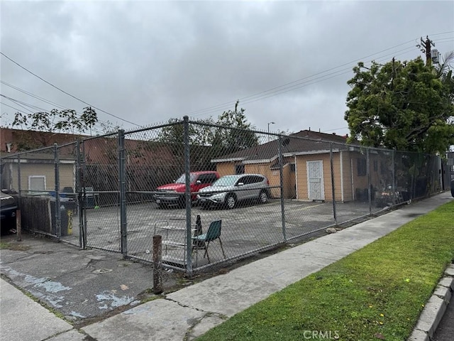 view of parking with fence and a gate