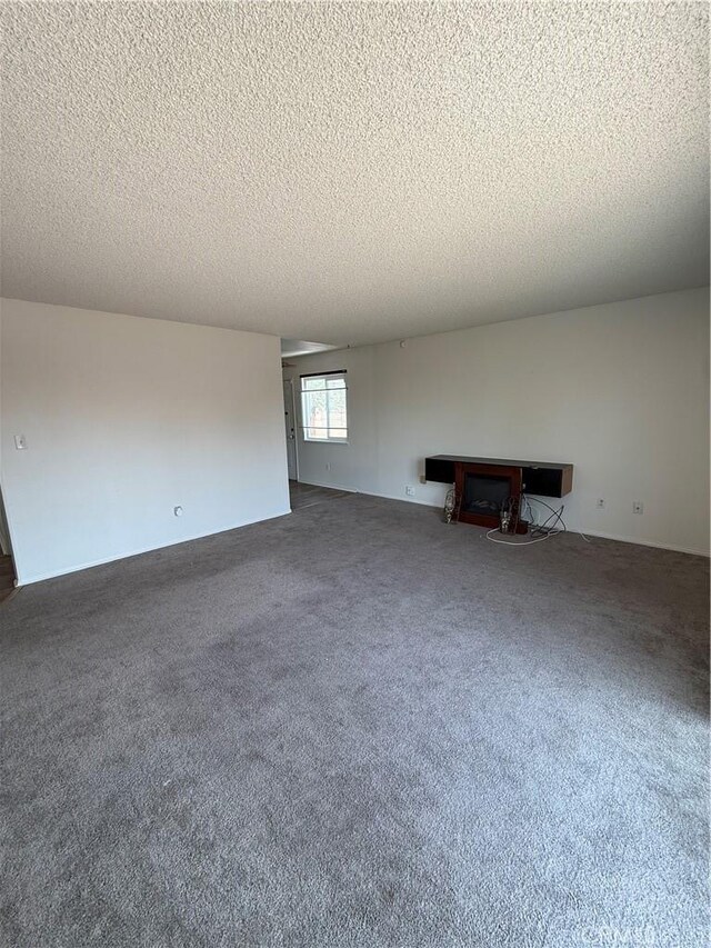 1564 Monte Vista Ave, Rosamond, CA 93560 - unfurnished living room featuring a textured ceiling and carpet floors