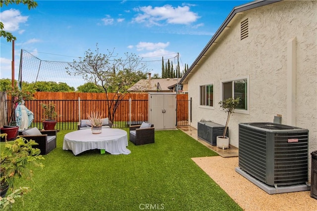 view of yard with a fenced backyard, a storage unit, an outbuilding, and central AC