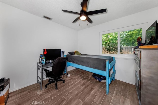 bedroom featuring visible vents, baseboards, ceiling fan, and wood finished floors