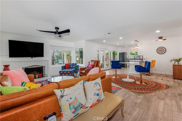 living room with recessed lighting, visible vents, light wood-style flooring, and a fireplace
