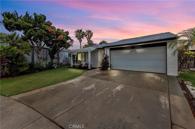 single story home with a garage, stucco siding, a yard, and driveway