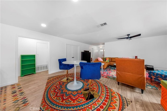living area with a ceiling fan, visible vents, and light wood-style floors