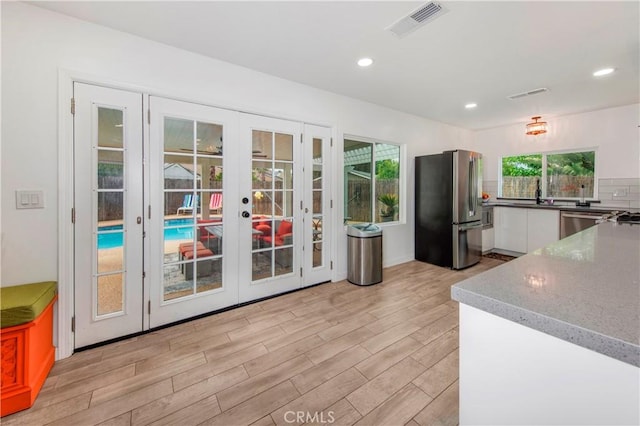 kitchen with french doors, light wood-style flooring, freestanding refrigerator, white cabinetry, and visible vents