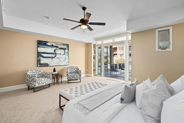 carpeted bedroom featuring access to exterior, ceiling fan, a tray ceiling, and baseboards