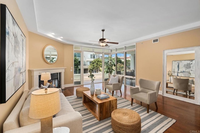 living room with wood finished floors, visible vents, ceiling fan, and baseboards