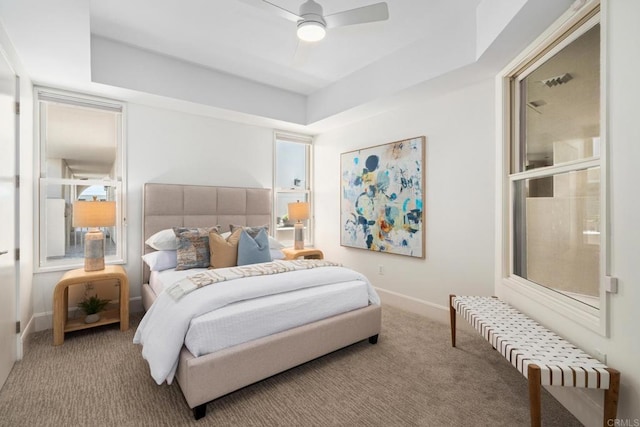 carpeted bedroom with a ceiling fan, a tray ceiling, and baseboards