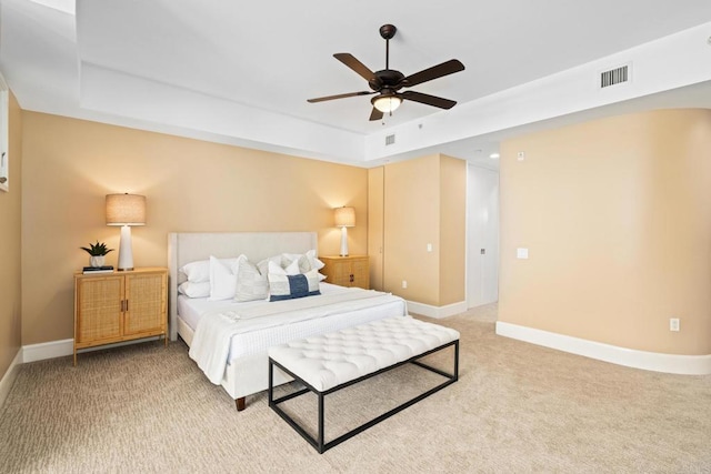 bedroom with baseboards, visible vents, a raised ceiling, and light colored carpet