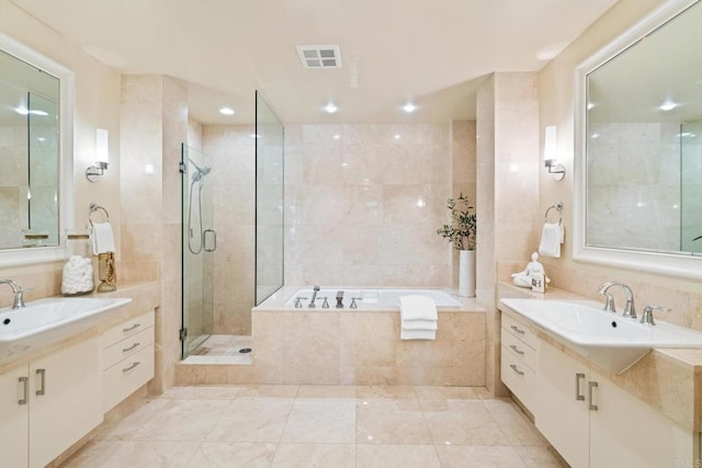 full bath featuring a sink, a bath, two vanities, and visible vents