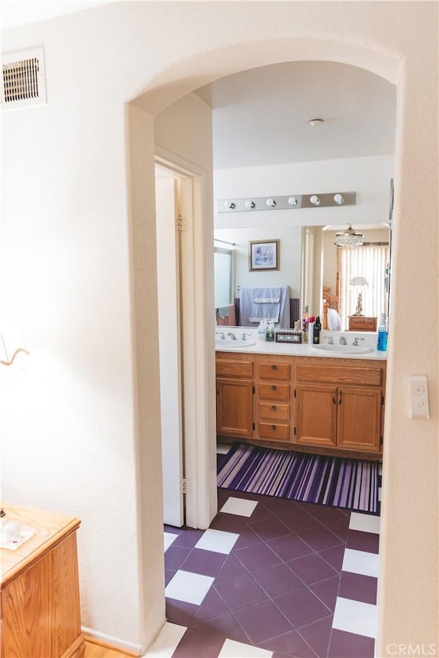 full bath with tile patterned floors, double vanity, a sink, and visible vents