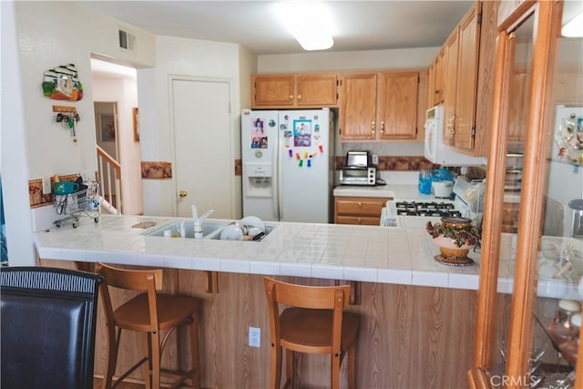 kitchen featuring white appliances, visible vents, a sink, and a peninsula