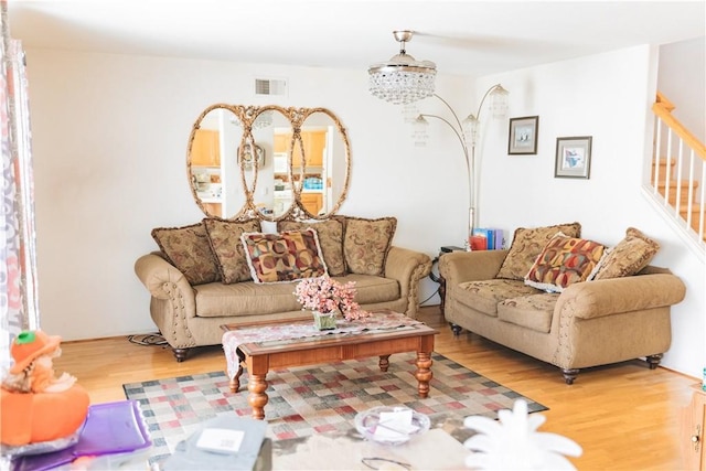 living room featuring stairway, visible vents, and wood finished floors