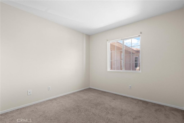 carpeted empty room featuring baseboards