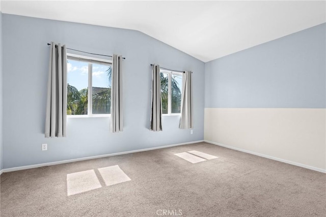 carpeted spare room with baseboards and vaulted ceiling