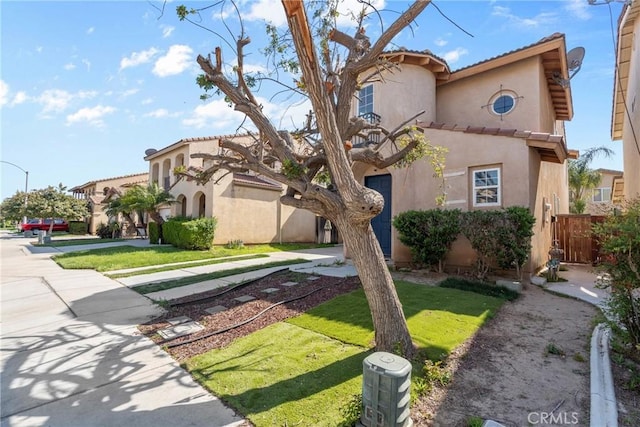mediterranean / spanish-style home with a tile roof, a front lawn, fence, and stucco siding
