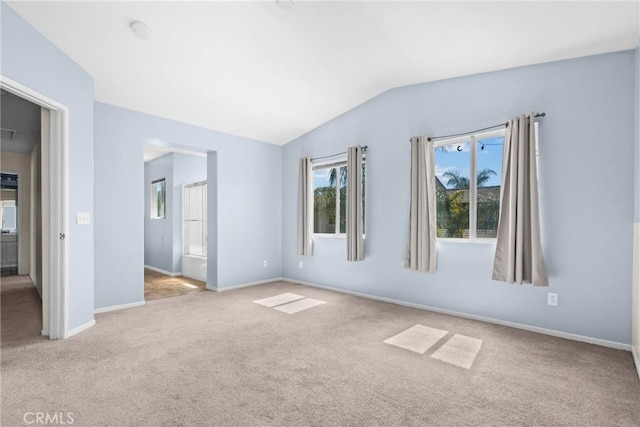 carpeted empty room with baseboards and lofted ceiling