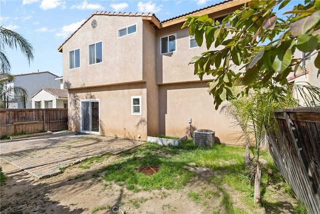 rear view of house with a fenced backyard, stucco siding, a patio area, a tile roof, and central AC unit