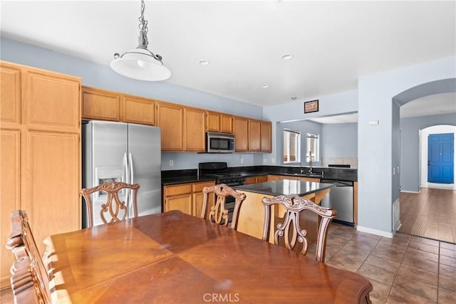 kitchen featuring pendant lighting, arched walkways, dark countertops, dark tile patterned floors, and stainless steel appliances