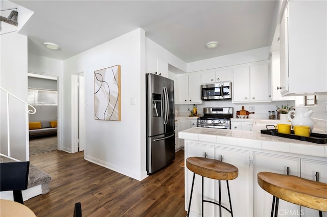 5263 E Paoli Way, Long Beach, CA 90803 - kitchen with a peninsula, white cabinets, dark wood-type flooring, appliances with stainless steel finishes, and tile countertops