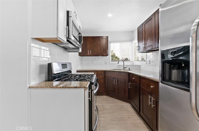 840 W 115th St, Los Angeles, CA 90044 - kitchen with stainless steel appliances, a sink, tasteful backsplash, light stone counters, and light wood-type flooring