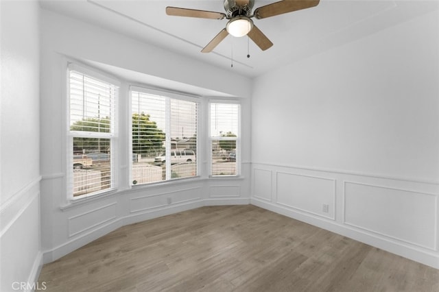 840 W 115th St, Los Angeles, CA 90044 - unfurnished room featuring light wood finished floors, a wainscoted wall, a ceiling fan, and a decorative wall