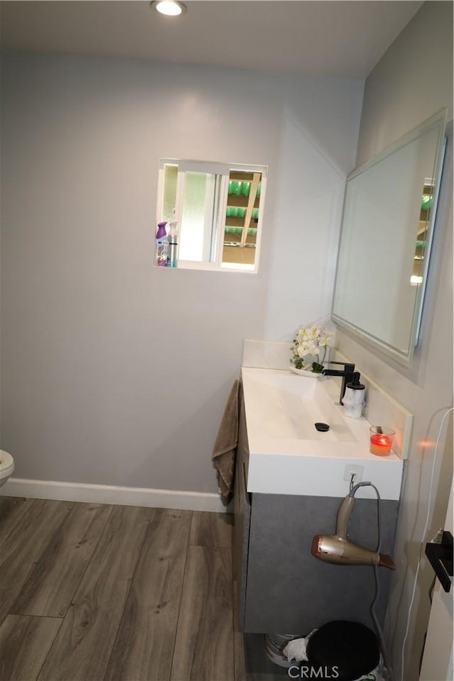 bathroom with baseboards, toilet, recessed lighting, vanity, and wood finished floors