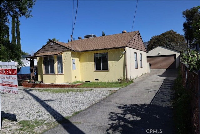 bungalow-style house featuring crawl space, a garage, stucco siding, an outbuilding, and roof with shingles