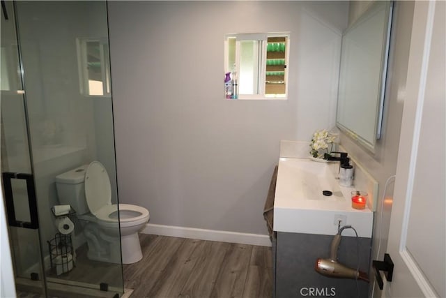 full bath with baseboards, toilet, a shower stall, vanity, and wood finished floors