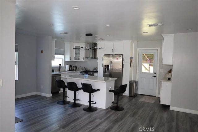 kitchen with stainless steel fridge with ice dispenser, visible vents, wall chimney exhaust hood, a sink, and light countertops
