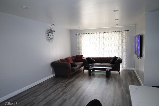 living room featuring dark wood-type flooring, baseboards, and recessed lighting
