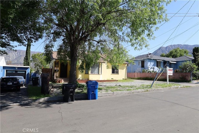 ranch-style house featuring driveway, a mountain view, stucco siding, and fence