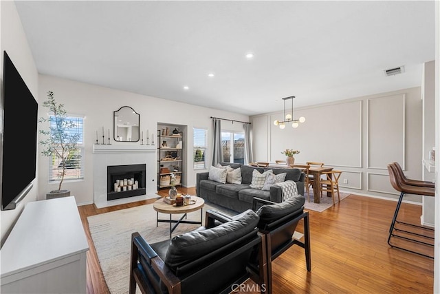 living area with light wood-style floors, a fireplace, visible vents, and recessed lighting